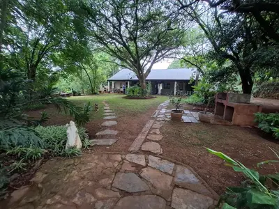 a yard with a stone walkway in front of a house at Plaas Klein Paradys in Blydebos