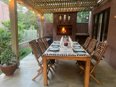 a dining room table with chairs and a fireplace at Plumtree House in Hoedspruit