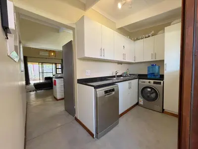 a kitchen with a sink and a washing machine at Plumtree House in Hoedspruit