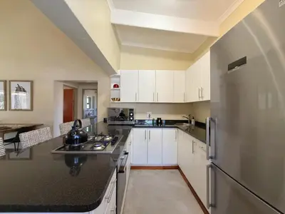 a kitchen with white cabinets and a stainless steel refrigerator at Plumtree House in Hoedspruit