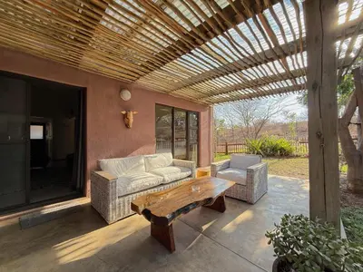 a patio with a couch and a table and a bench at Plumtree House in Hoedspruit