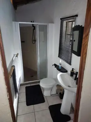 a bathroom with a toilet and a sink and a shower at Uitpak in Barberton