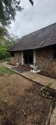 a stone house with a large window in a yard at Uitpak in Barberton