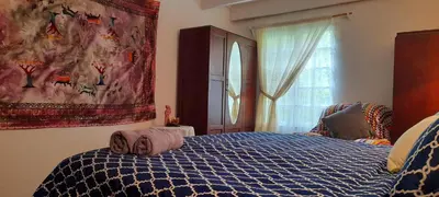 a bedroom with a bed with a blue comforter and a window at The Dutch House in Dullstroom