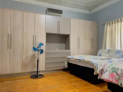 a bedroom with a bed and a fan and cabinets at Urban Oasis Guest House in Pretoria