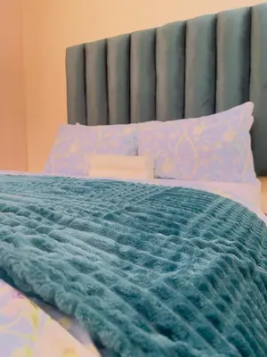 a bed with a blue comforter and pillows at Urban Oasis Guest House in Pretoria