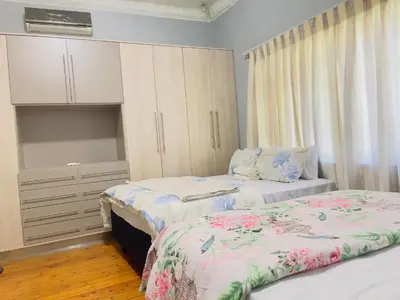 a bedroom with two beds and a cupboard and curtains at Urban Oasis Guest House in Pretoria