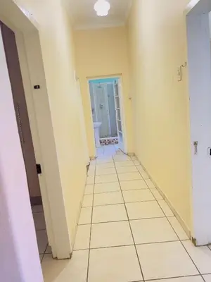 a hallway with yellow walls and a tile floor at Urban Oasis Guest House in Pretoria