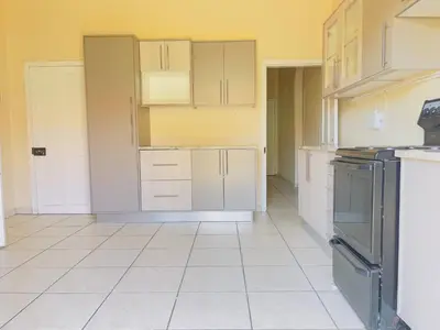 an empty kitchen with white cabinets and appliances at Urban Oasis Guest House in Pretoria
