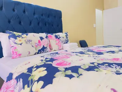 a bed with a blue headboard and pink flowers at Urban Oasis Guest House in Pretoria