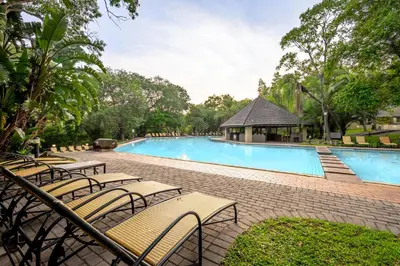 a large swimming pool with chairs and a gazebo at First Group Sanbonani Resort in Hazyview