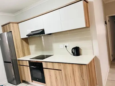 a kitchen with white cabinets and a black appliance at The Blyde in Pretoria