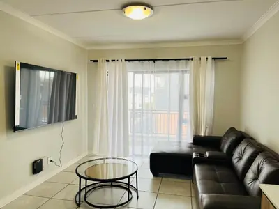 a living room with a leather couch and a glass table at The Blyde in Pretoria