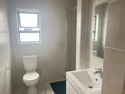 a white bathroom with a toilet and a sink at The Blyde in Pretoria
