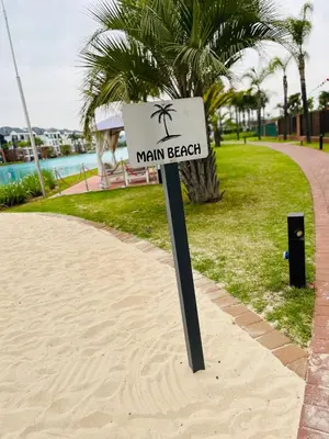 a sign in the sand on a beach with a palm tree at The Blyde in Pretoria