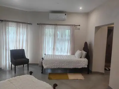 a bedroom with a bed and a chair and a window at Villa in the Wild in Marloth Park