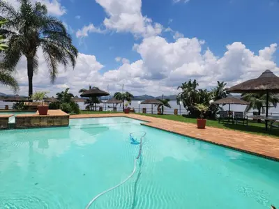 a swimming pool at a resort with trees and umbrellas at BondMakers Hidden Gem in Hartbeespoort