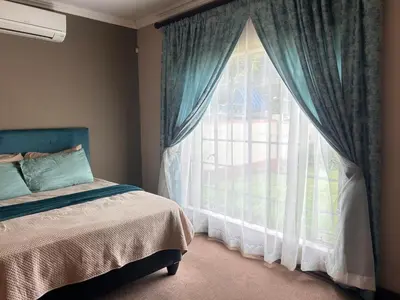 a bedroom with a bed and a large window at 3 Bed Holiday Home in Witbank