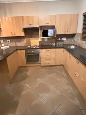 an empty kitchen with wooden cabinets and a stove at 3 Bed Holiday Home in Witbank