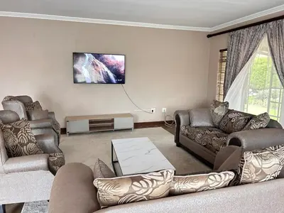 a living room with couches and a tv on the wall at 3 Bed Holiday Home in Witbank