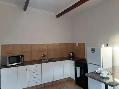 a kitchen with white cabinets and a white refrigerator at Shalom Cottage in Kempton Park