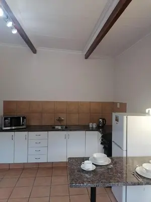 a kitchen with white cabinets and a counter top at Shalom Cottage in Kempton Park