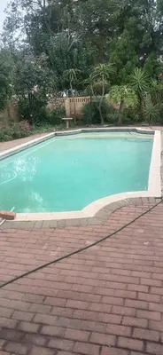 a swimming pool in a yard with a brick driveway at Shalom Cottage in Kempton Park