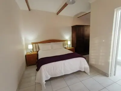 a bedroom with a bed and two night stands with lamps at Shalom Cottage in Kempton Park
