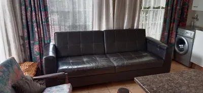 a leather couch in a living room with a washing machine at Shalom Cottage in Kempton Park