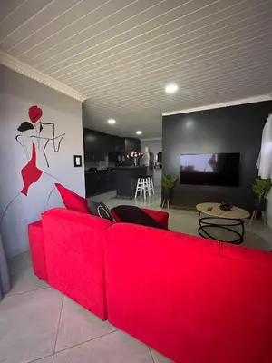a red couch in a living room with a kitchen at Hannie Pot in Pretoria