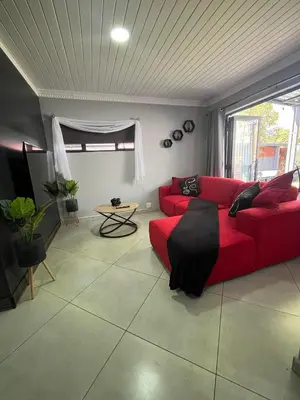 a living room with a red couch and a table at Hannie Pot in Pretoria