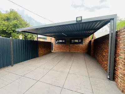 a garage with a roof over a brick wall at Hannie Pot in Pretoria