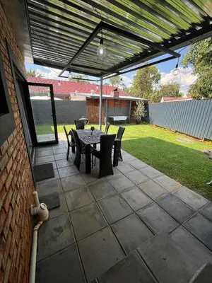 a patio with a table and chairs under a pergola at Hannie Pot in Pretoria