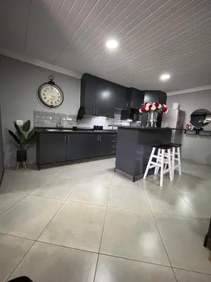 a kitchen with black cabinets and a clock on the wall at Hannie Pot in Pretoria