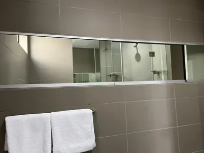 a bathroom with a large mirror and white towels at 15 On Slice in Polokwane