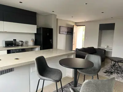 a kitchen and living room with a table and chairs at 15 On Slice in Polokwane