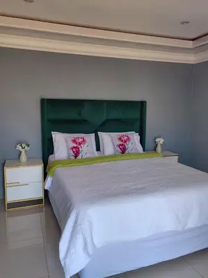 a bedroom with a large bed with a green headboard at Marula Tree Lodge in Moletlane