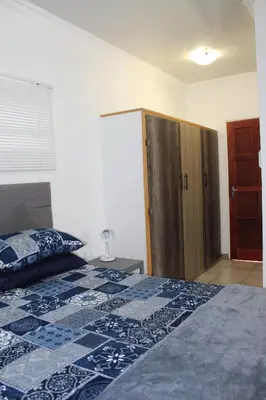 a bedroom with a bed and a wooden cabinet at Angel Cottage in Tzaneen