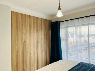 a bedroom with a wooden cabinet next to a window at The Blyde in Pretoria