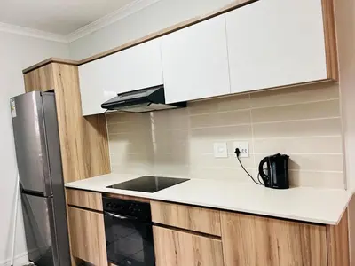 a kitchen with white cabinets and a black appliance at The Blyde in Pretoria