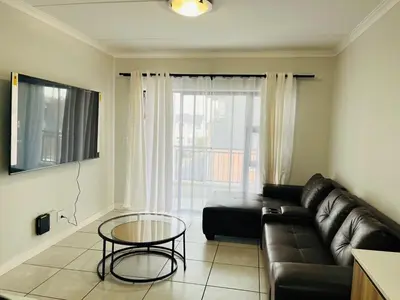 a living room with a leather couch and a glass table at The Blyde in Pretoria