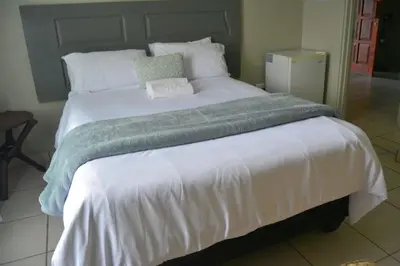 a large white bed with a green blanket on it at Rural Villa Guesthouse in Naledi
