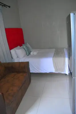 a small bedroom with a bed and a couch at Rural Villa Guesthouse in Naledi