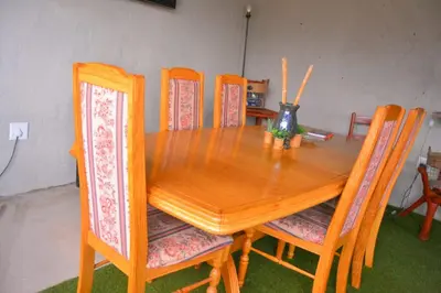 a wooden dining room table with four chairs and a table at Rural Villa Guesthouse in Naledi