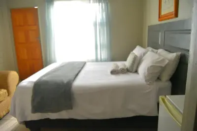 a bedroom with a large white bed with a window at Rural Villa Guesthouse in Naledi