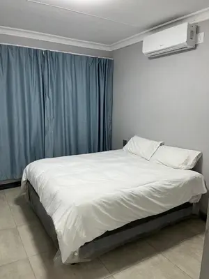 a bedroom with a large white bed with a blue curtain at Skylabs Housing in Polokwane