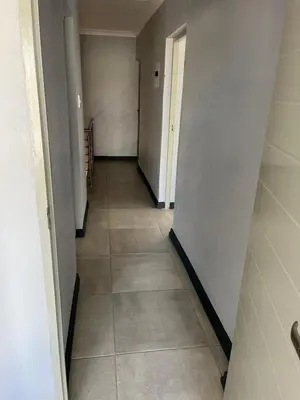 a hallway with a tile floor and white walls at Skylabs Housing in Polokwane