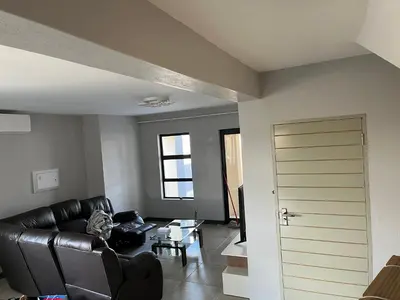 a living room with a leather couch and a door at Skylabs Housing in Polokwane