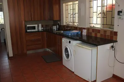 a kitchen with a washing machine and a counter at Doornboom Guesthouse in Pretoria