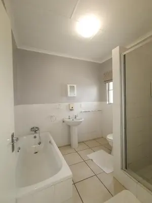 a white bathroom with a tub and a sink at Loerie Guesthouse in Hoedspruit
